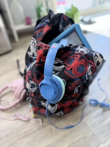 Kids backpack with wired headphones and a blue Fire tablet for travel. 