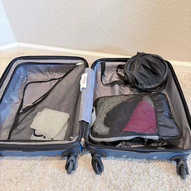 Blue suitcase open with packing cubes and foldable laundry hamper
