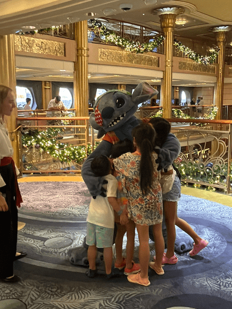 Kids hugging Stitch in pirate gear on the Disney Cruise. 