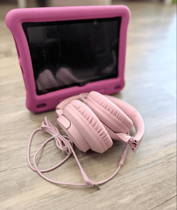 Pink wired headphones with Fire tablet with a pink case. 
